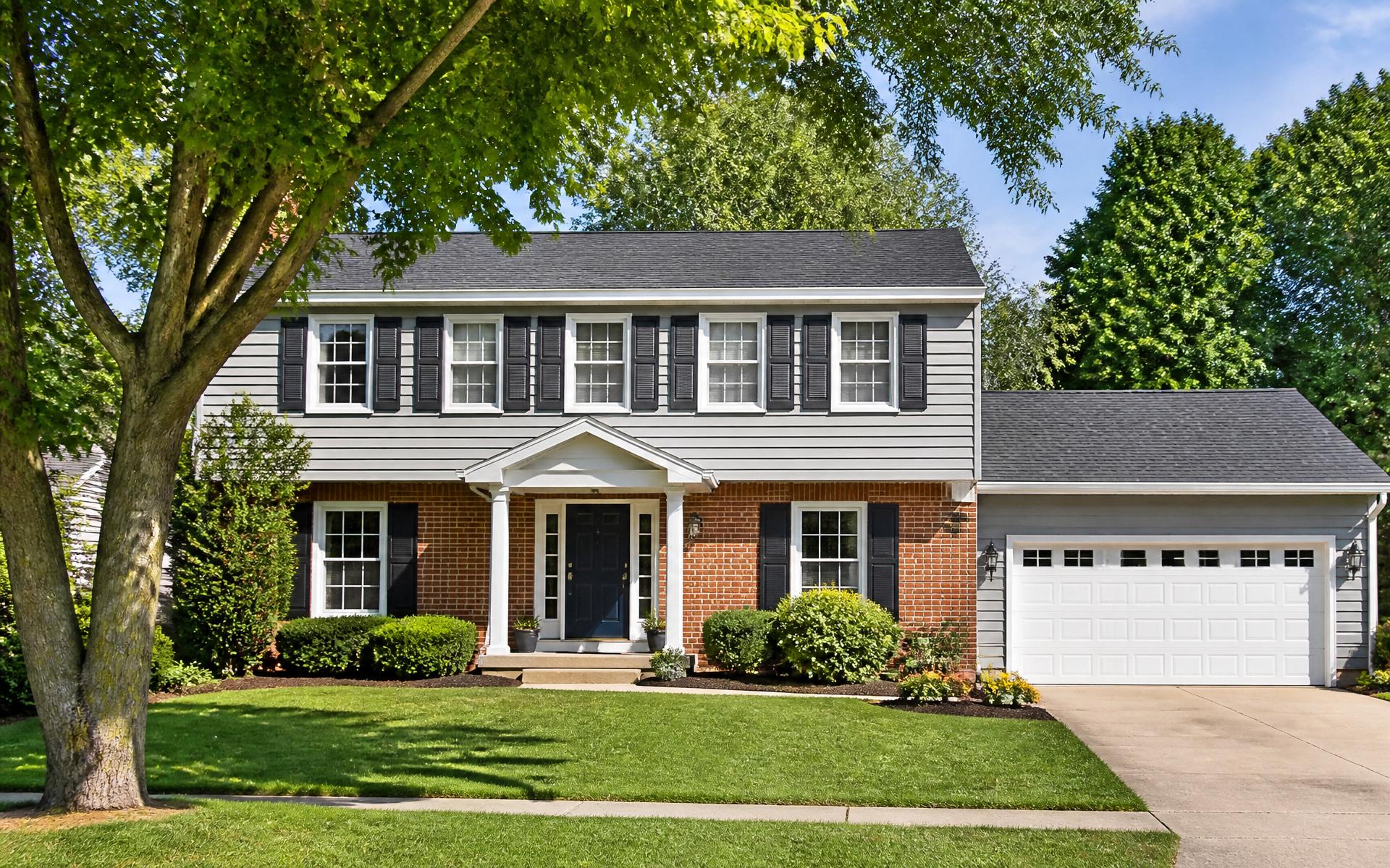 Classic Midwestern two-story Colonial home in Northern Illinois with brick and lap siding, mature trees, and manicured landscaping
